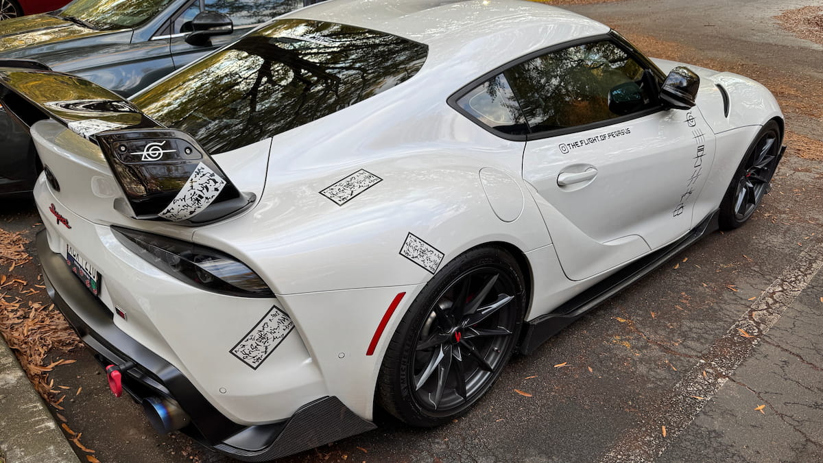 White sports car with black rims on a road